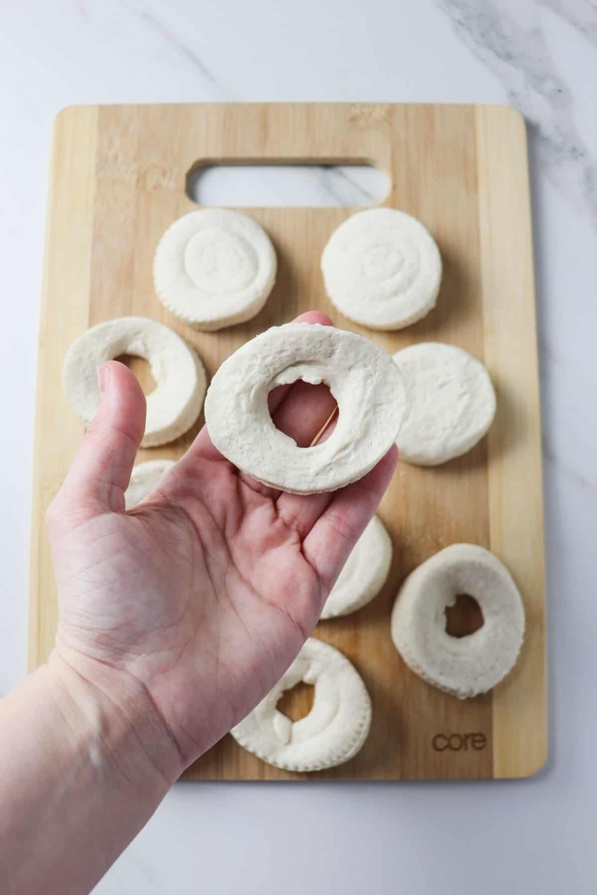 pinching a hole in biscuit to make a donut shape