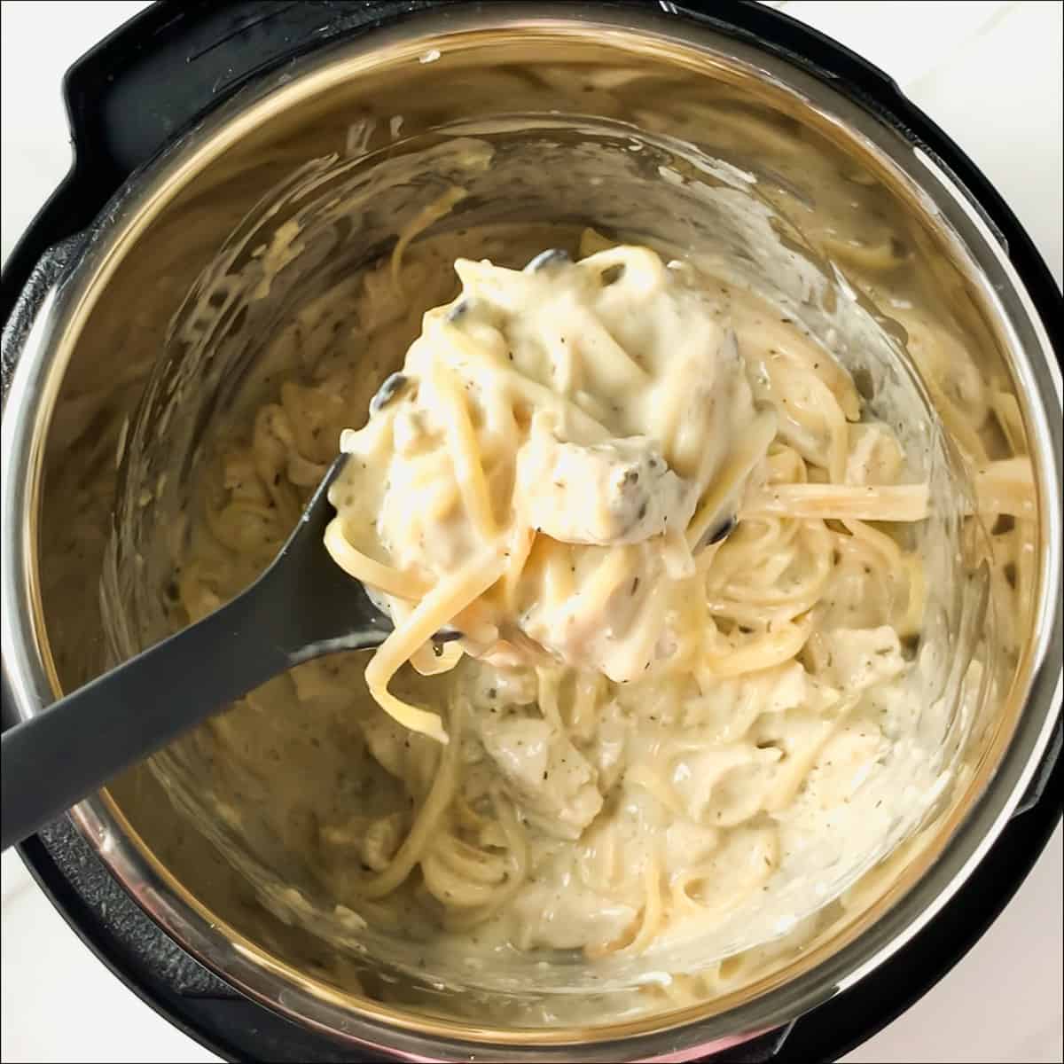 scooping out a spoonful of chicken alfredo from the instant pot