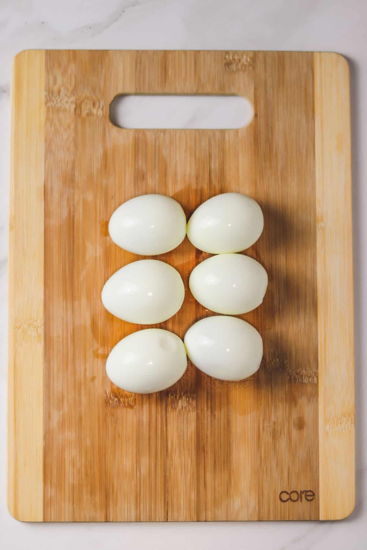 six peeled hard boiled eggs on cutting board