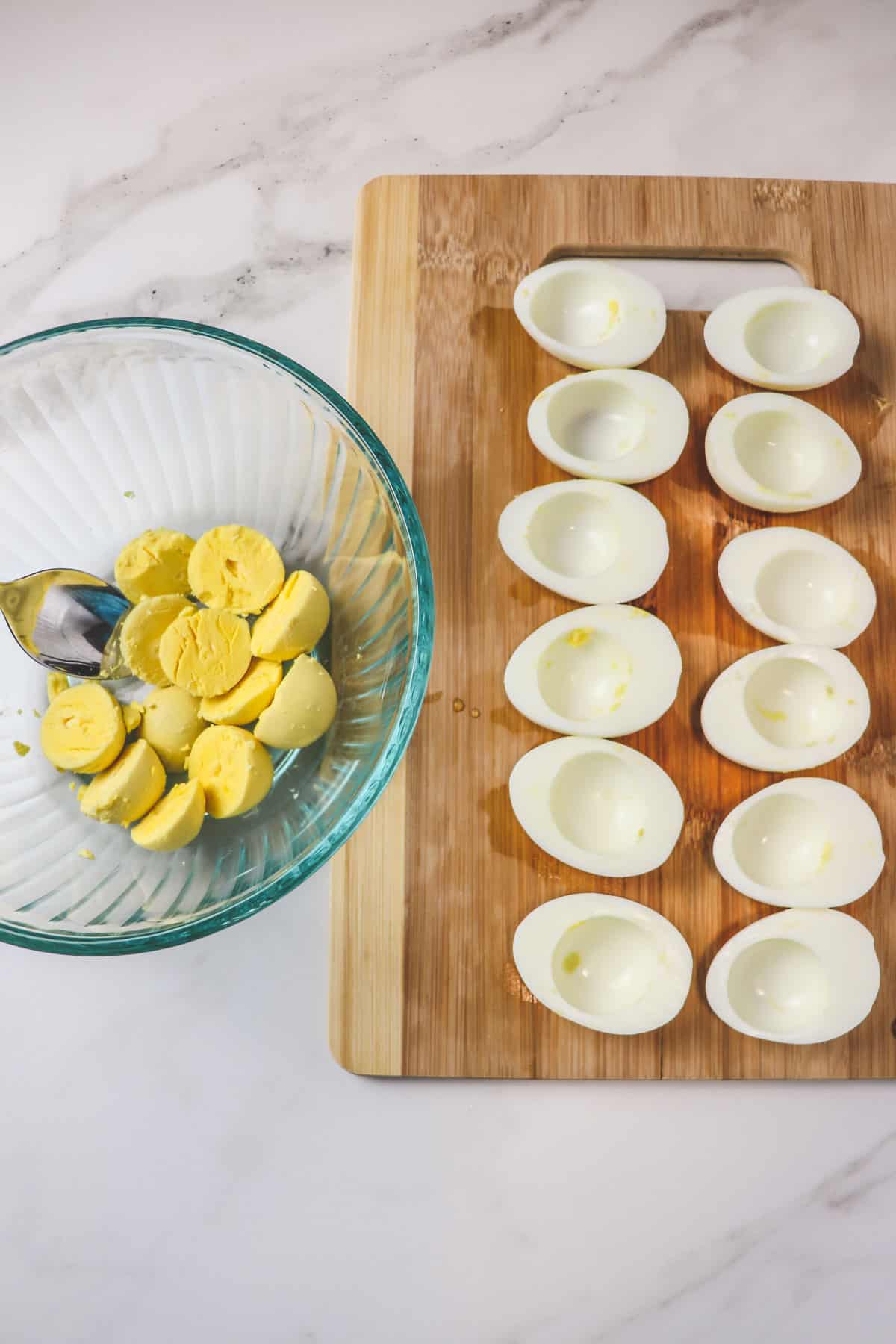 scooping cooked egg yolks out of egg whites