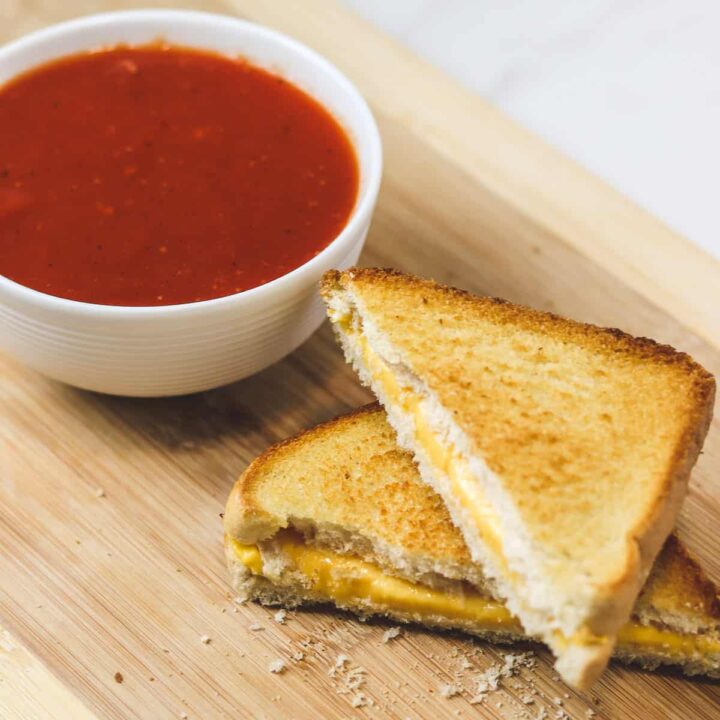 air fryer grilled cheese cut in half with a bowl of tomato soup