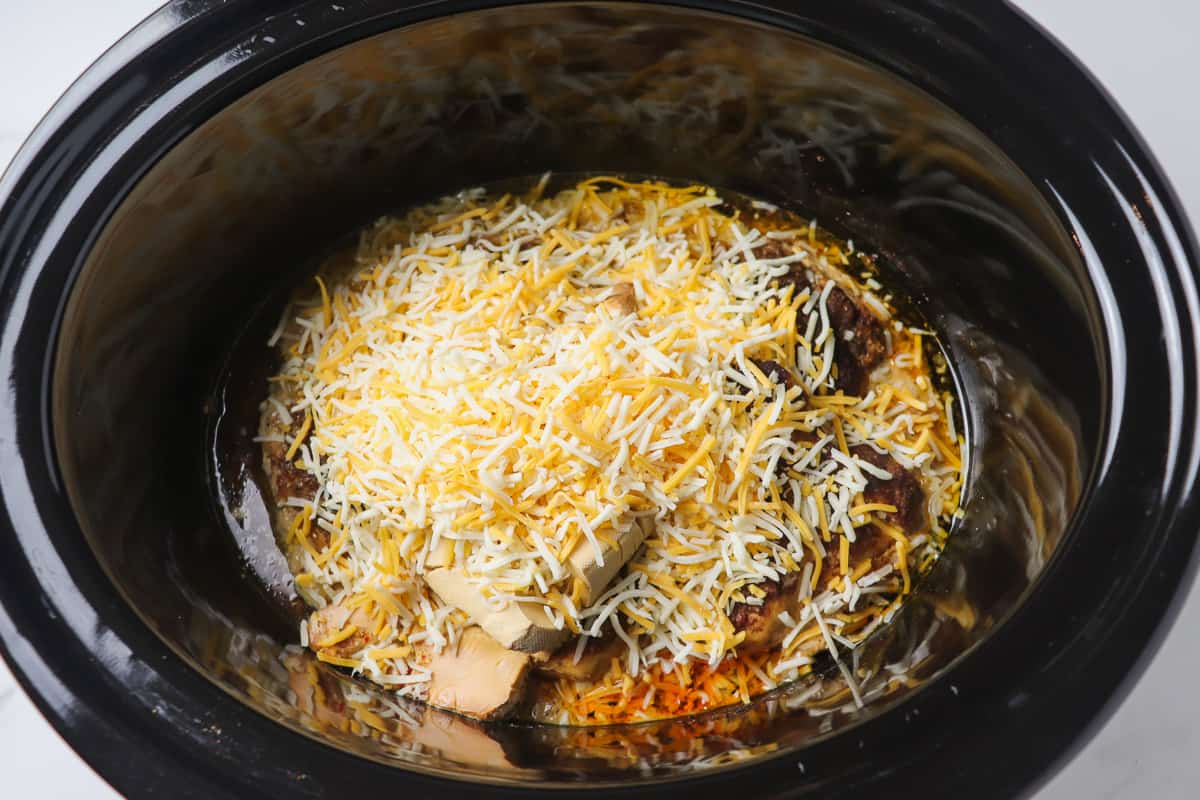 adding shredded cheese into crock pot after chicken is cooked
