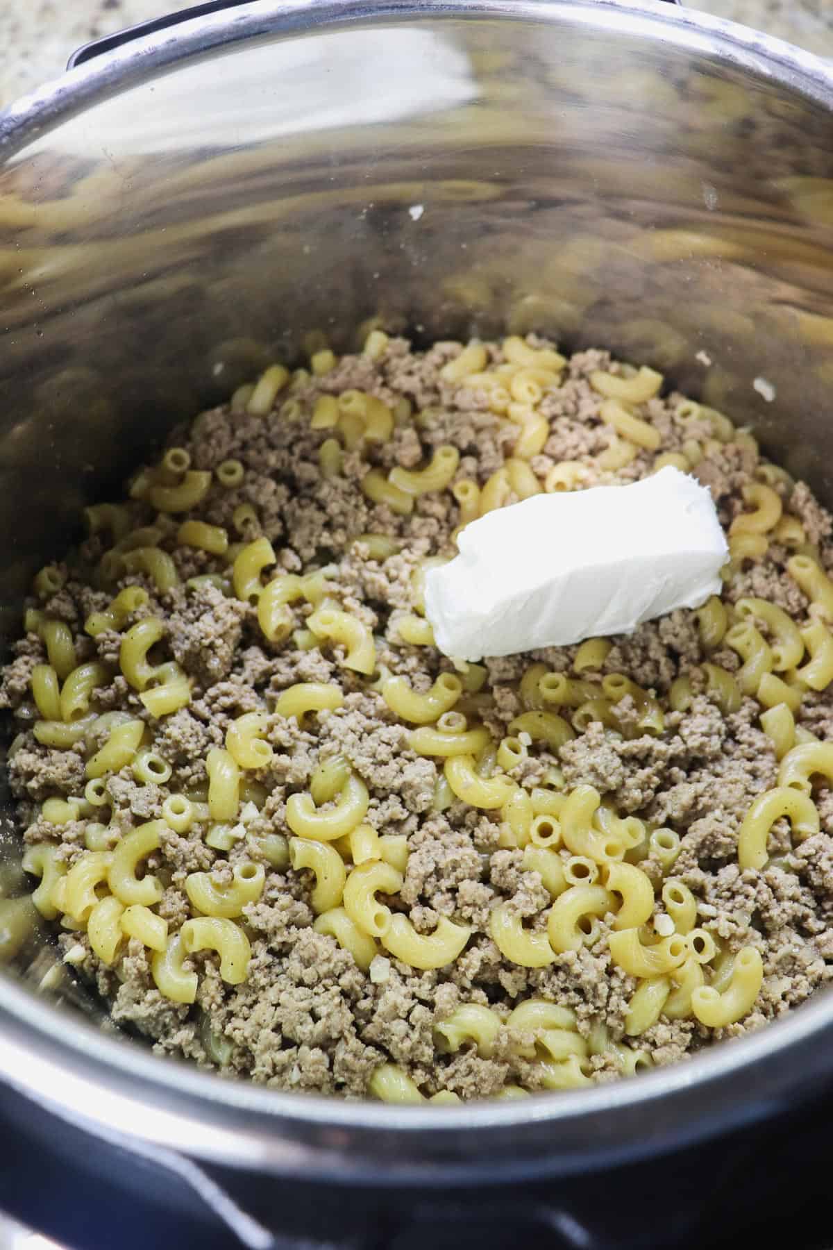 adding cream cheese to cooked noodles and ground turkey in instant pot