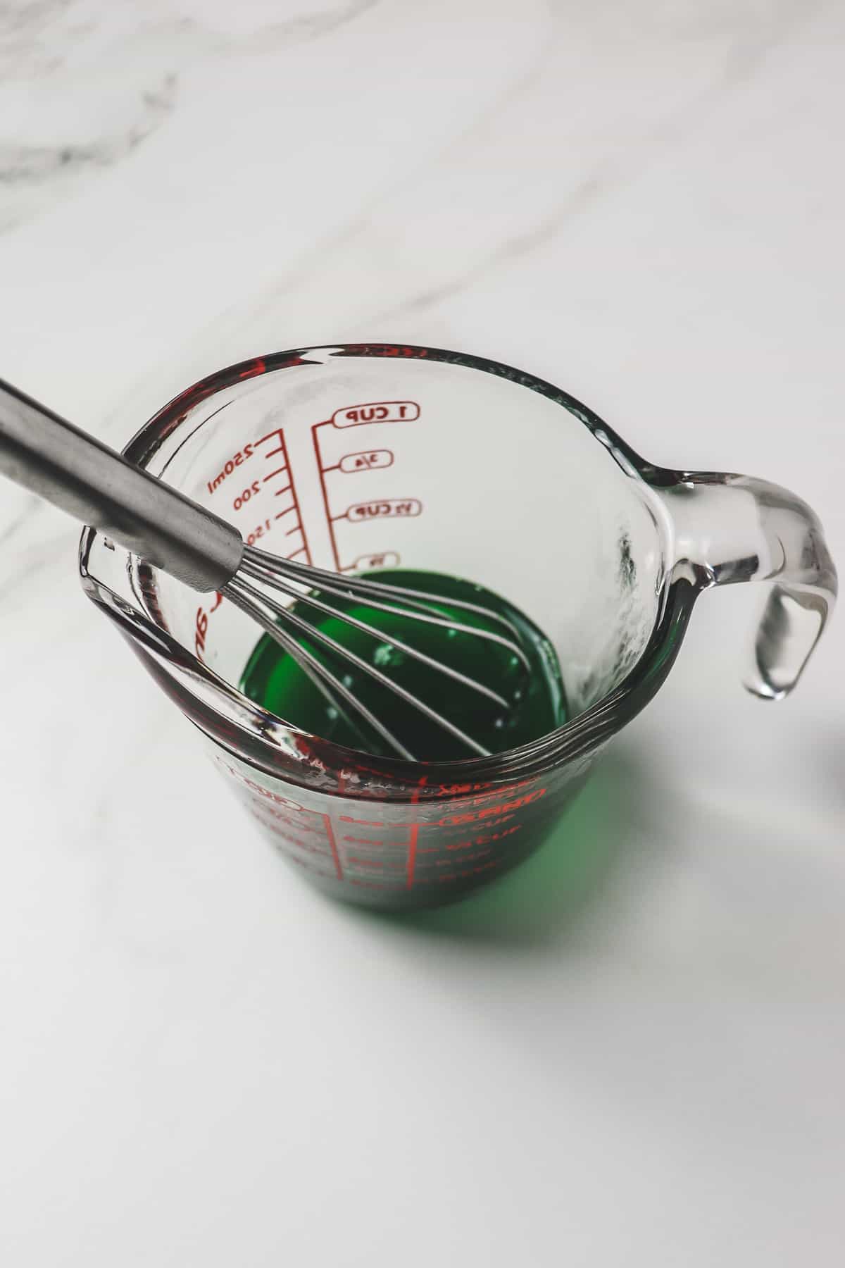 whisking the lime jello powder into boiling water in a small measuring cup