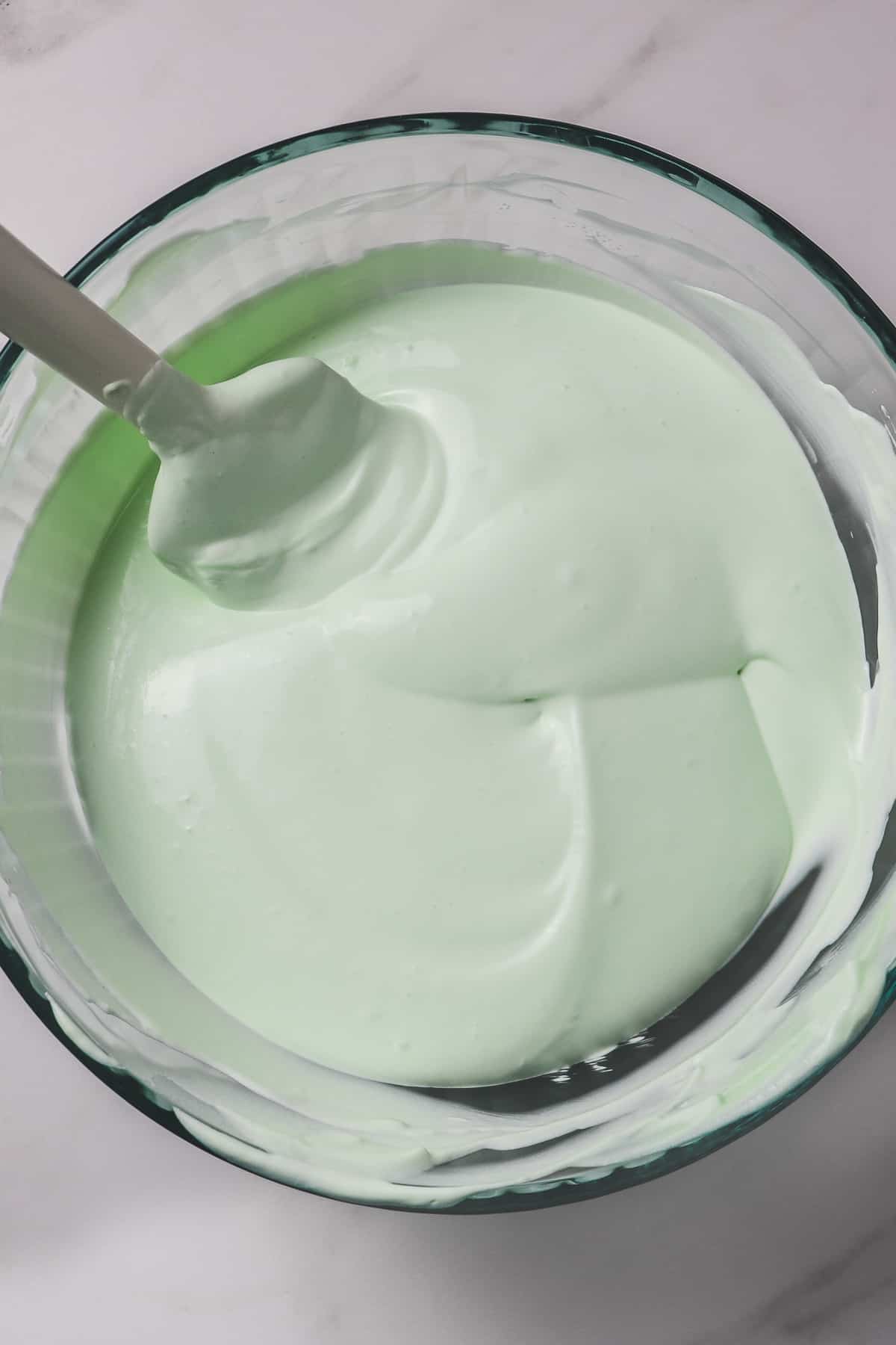 folding the cool whip into the key lime pie filling mixture in a glass bowl