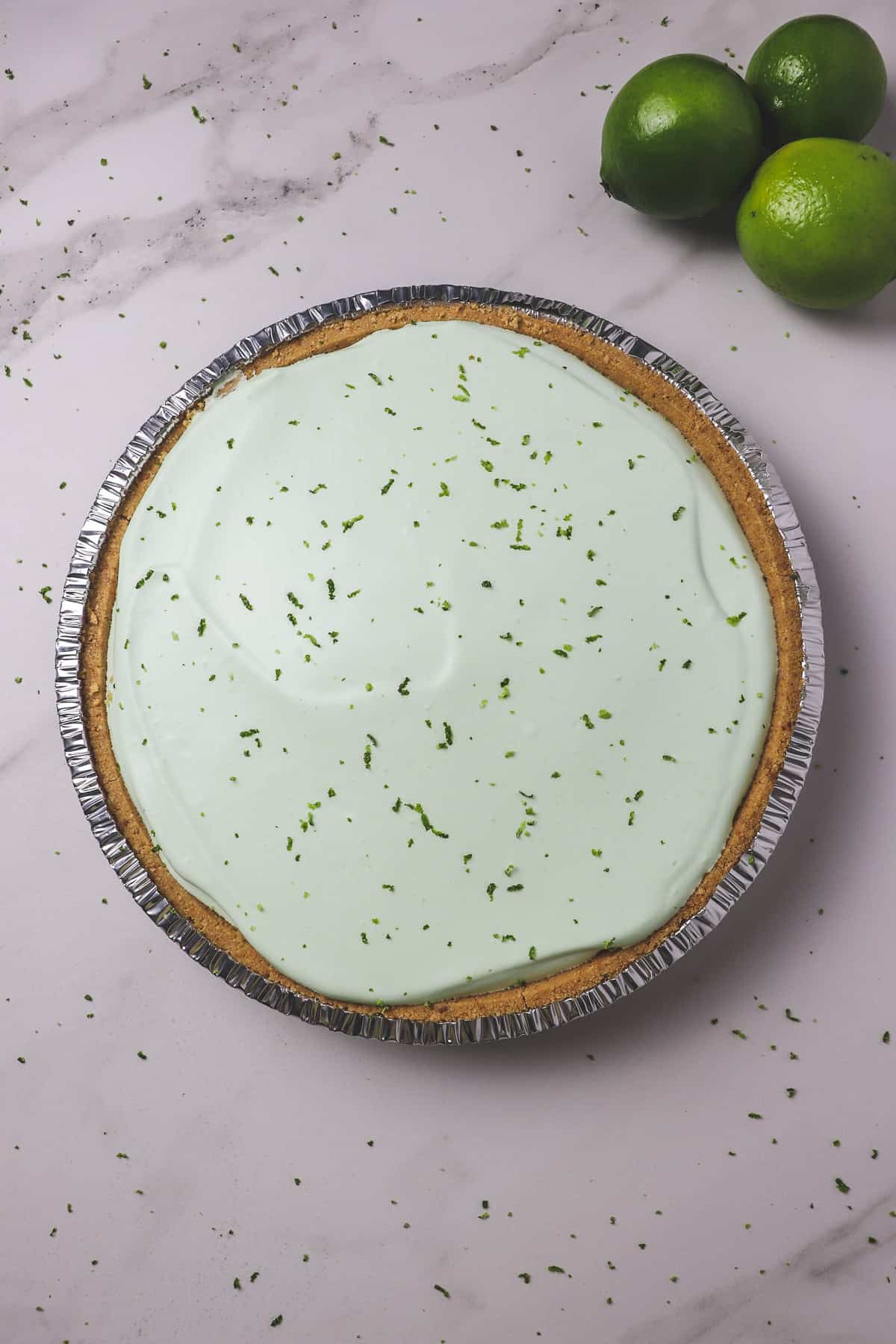 finished no-bake key lime pie with lime zest on top and 3 limes