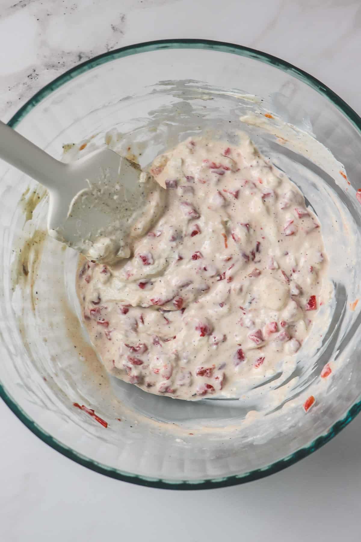 cream cheese, sour cream, and pimentos mixed in glass bowl