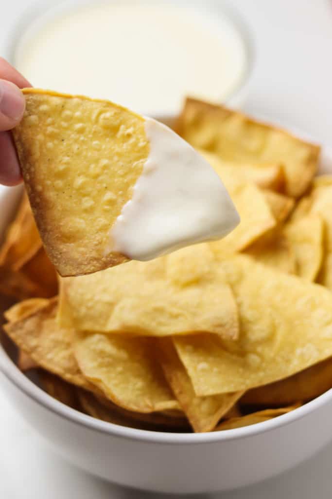 dipping a tortilla chip in queso