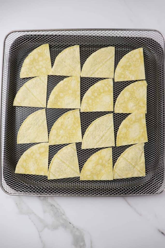 uncooked tortilla chips loaded into air fryer basket