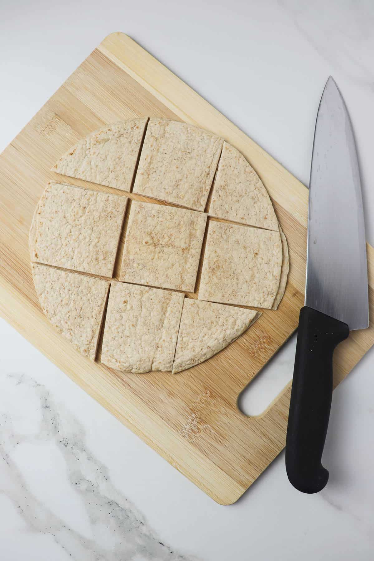 cutting a low carb tortilla into thirds on a wood cutting board