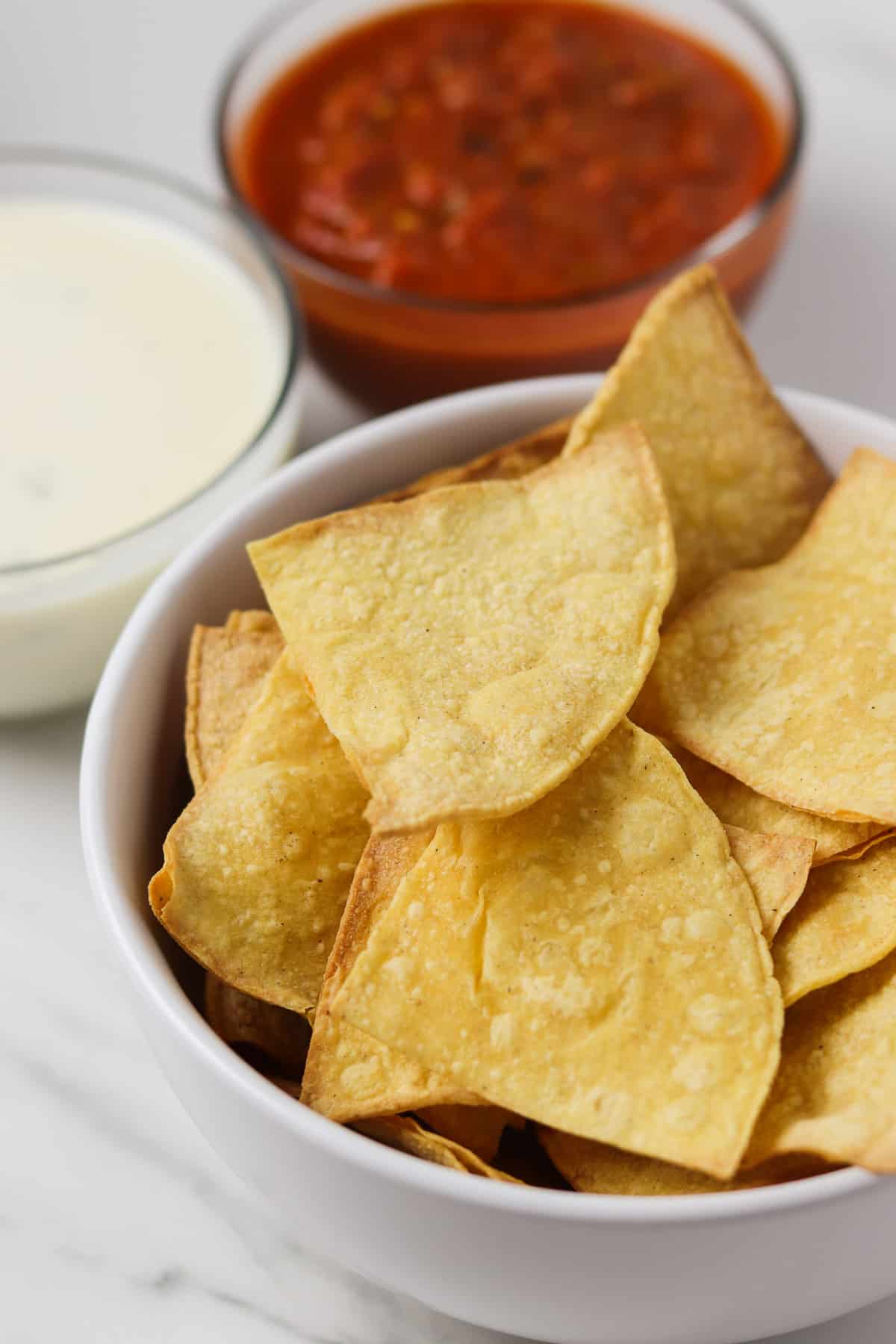 air fryer corn tortilla chips in a bowl with queso and salsa in the background