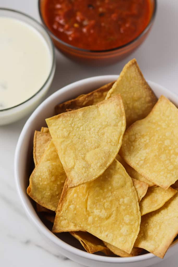 air fryer corn tortilla chips in a bowl with queso and salsa