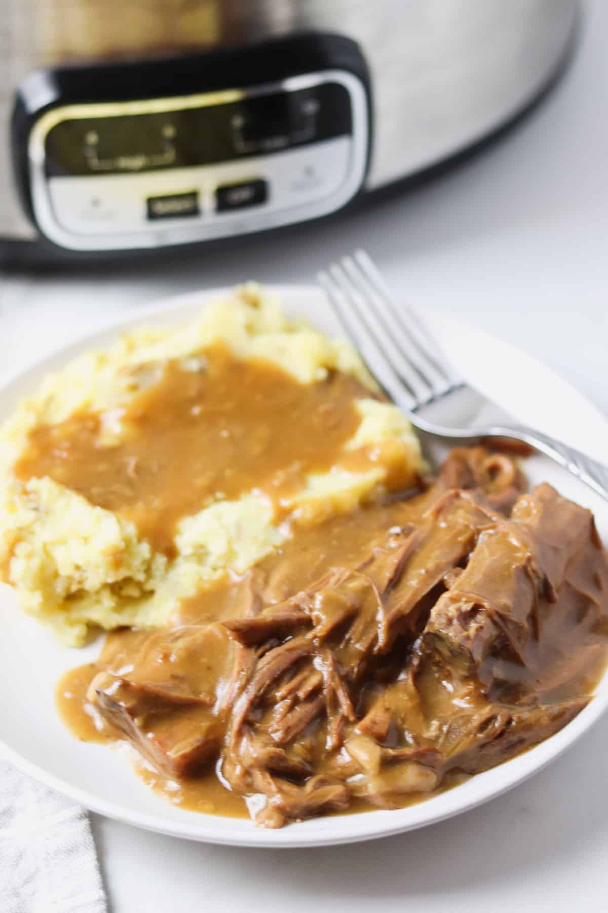 crock pot roast with gravy and a side of mashed potatoes