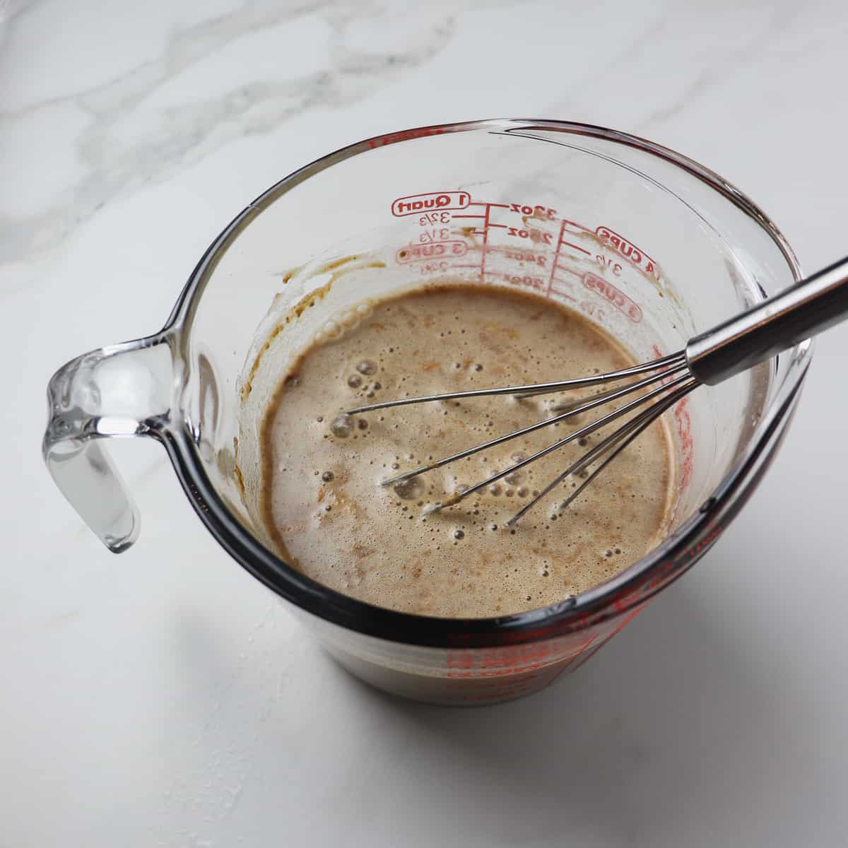 mixing the gravy and water mixture in a glass measuring cup