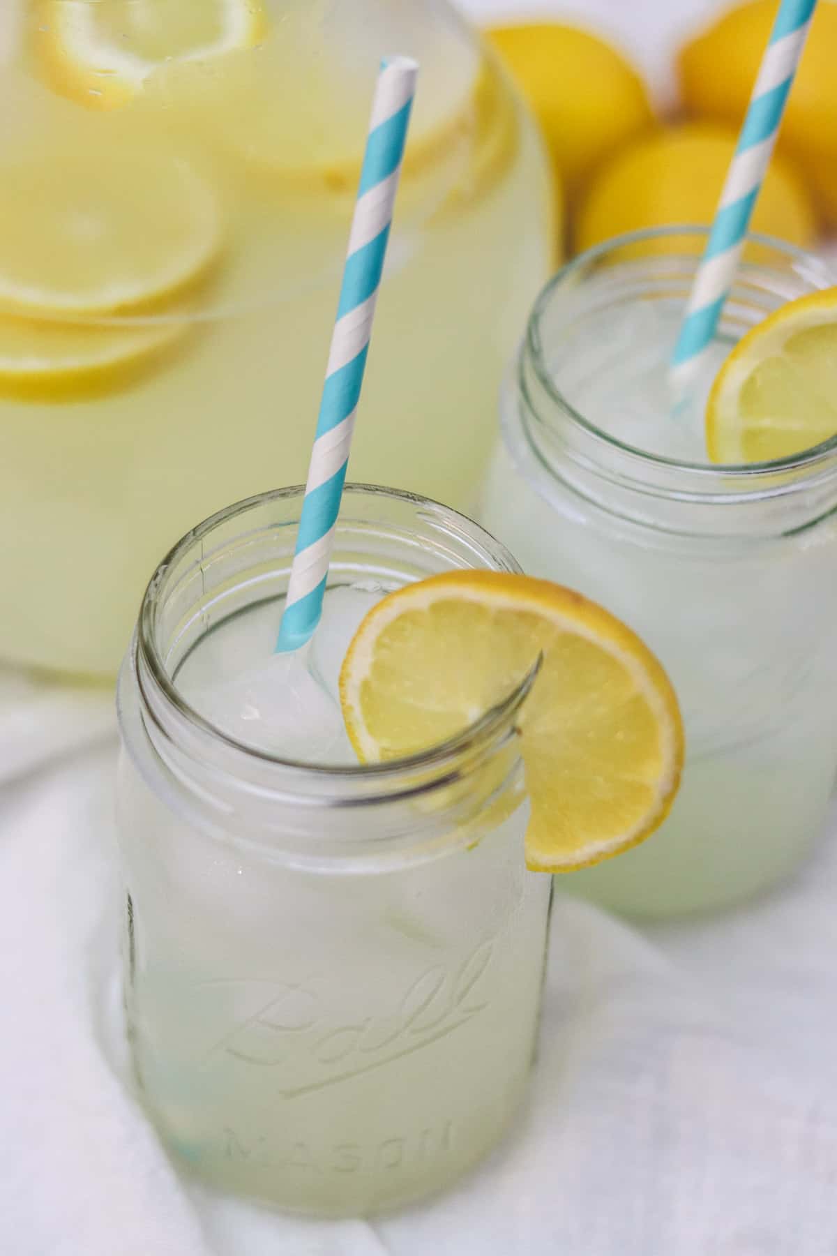 sugar free lemonade in a mason jar with pitcher of lemonade in background
