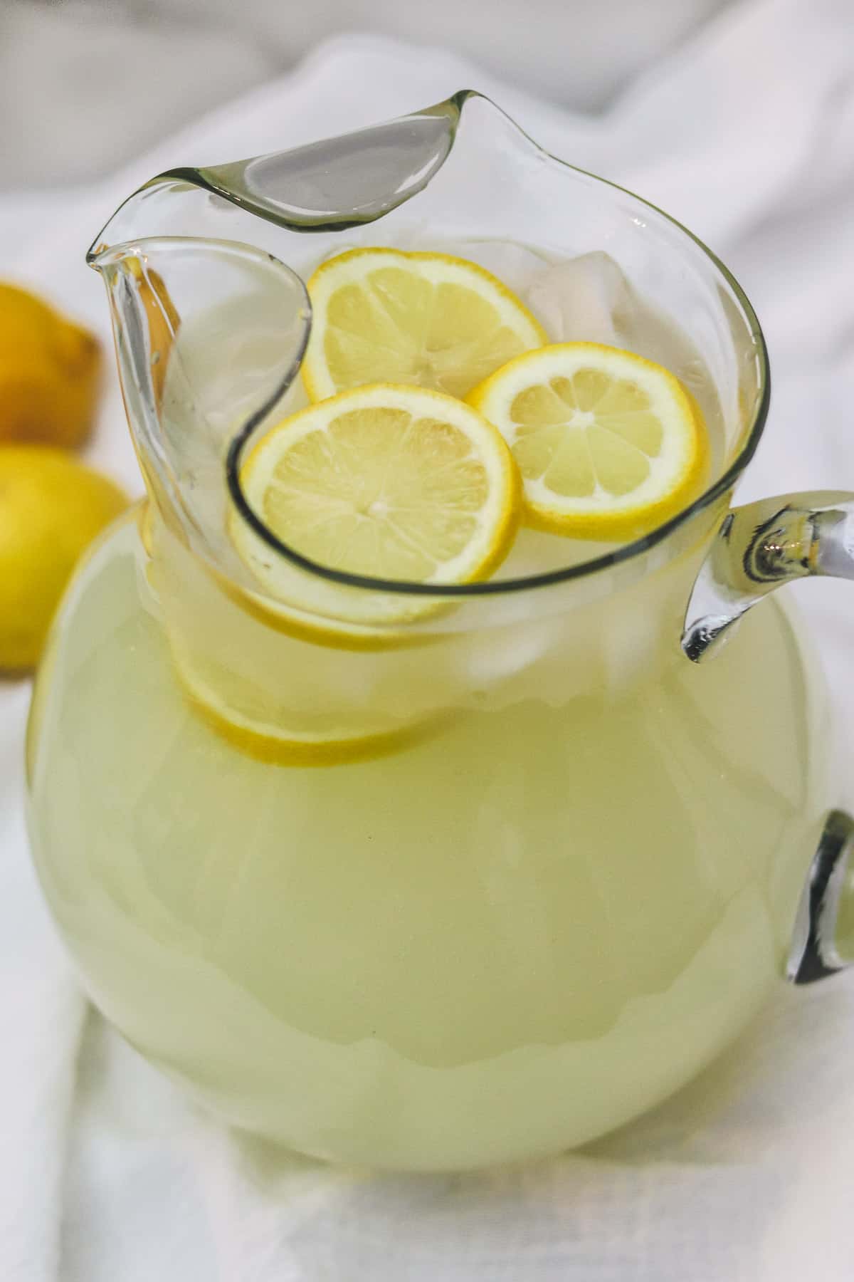 pitcher of sugar free lemonade with lemons and ice cubes