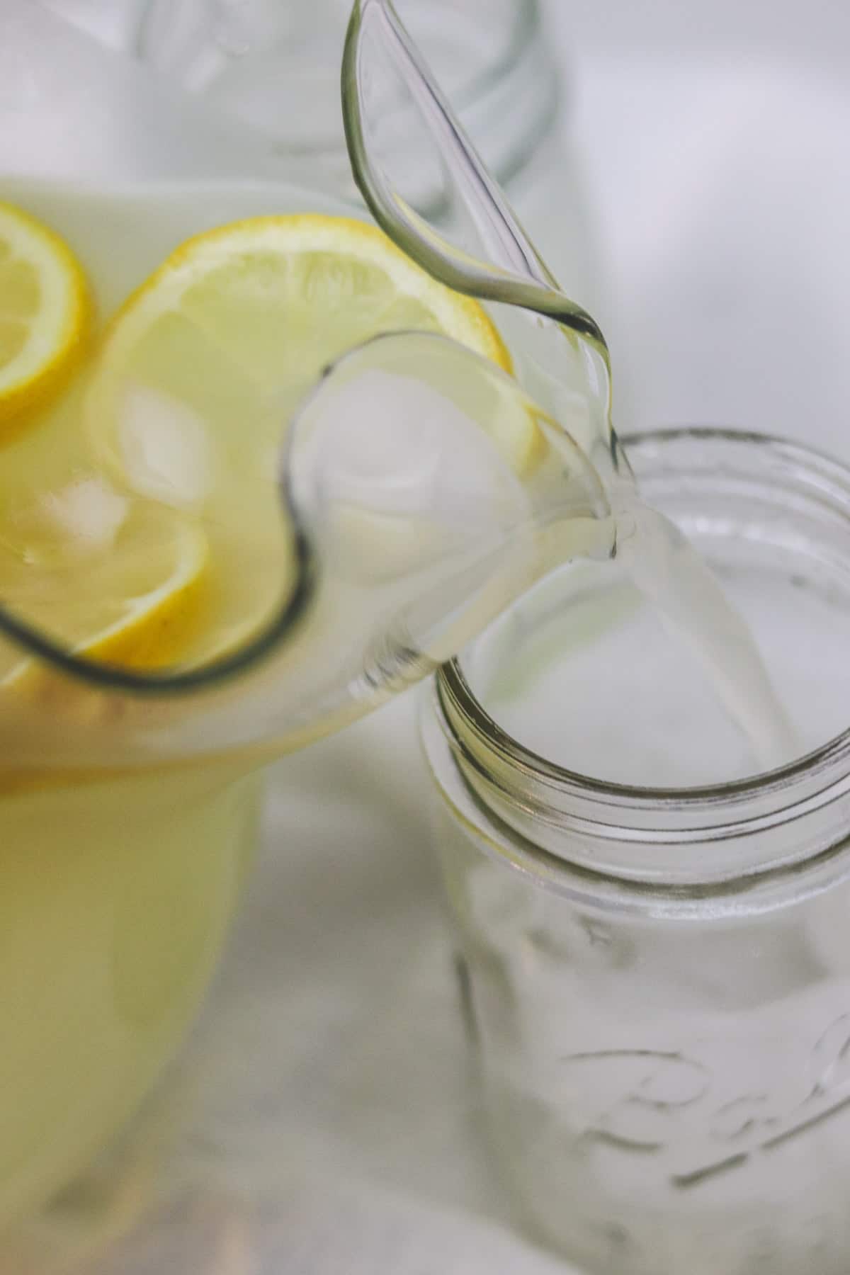 pouring a pitcher of lemonade into a jar