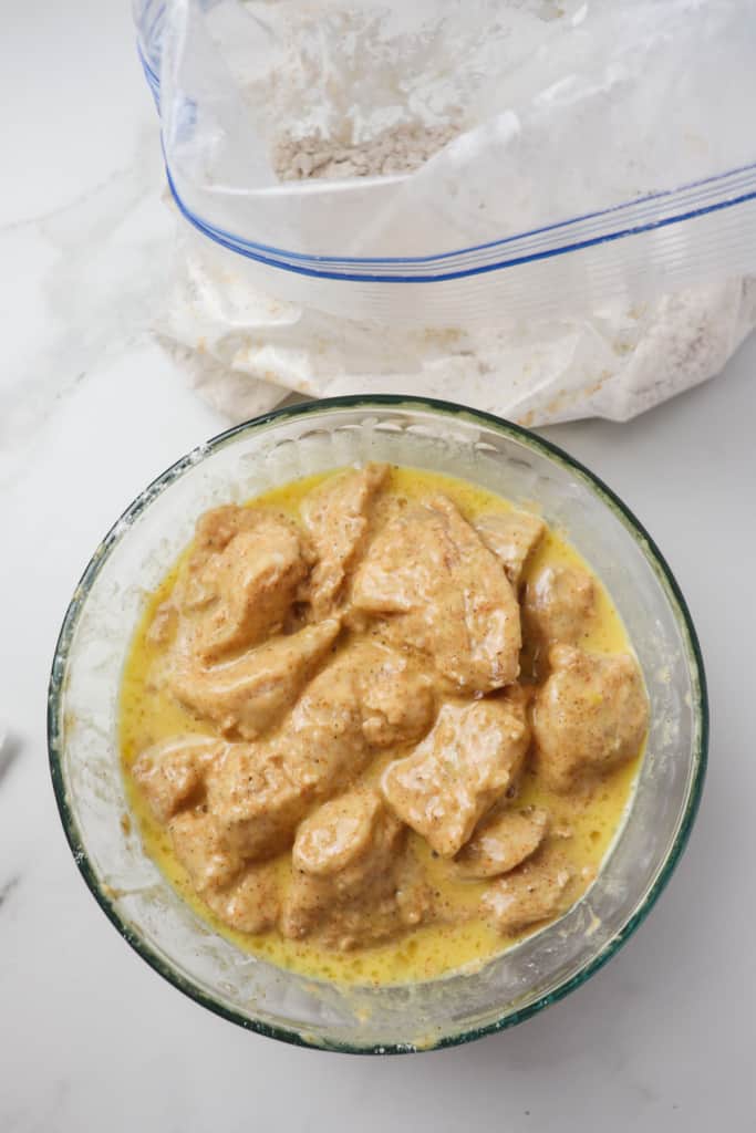 chicken nuggets in bowl with egg and milk mixture