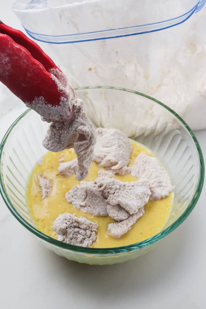 dipping floured nuggets into bowl with egg mixture