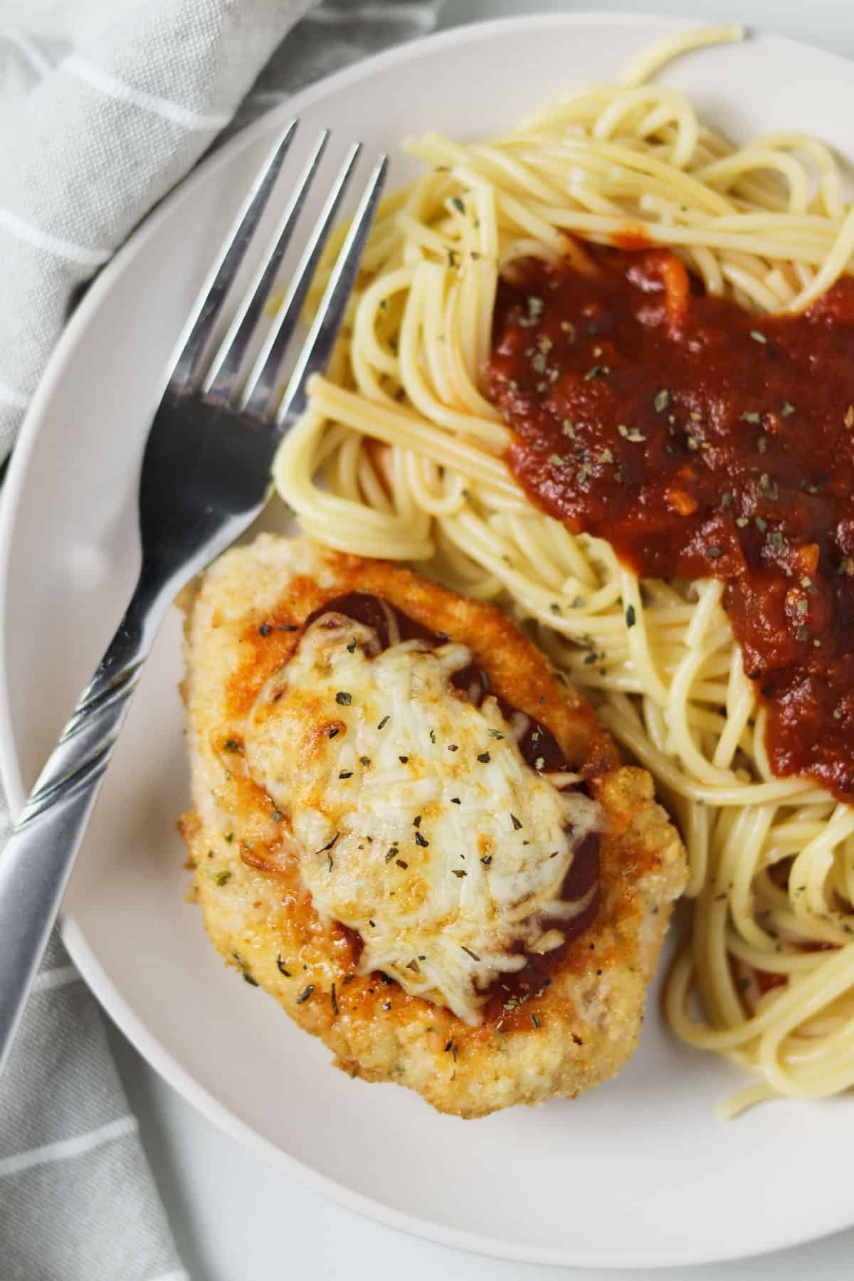 air fryer chicken parmesan on white plate with spaghetti and marinara
