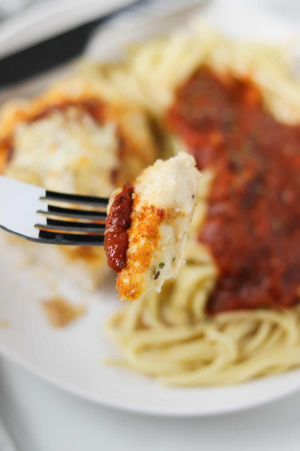 taking a bite of chicken parmesan with a fork