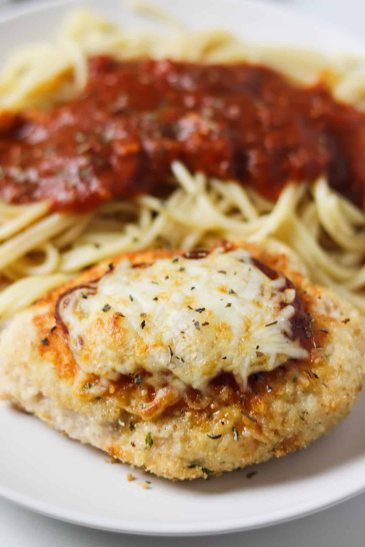 air fryer chicken parmesan on white plate with spaghetti
