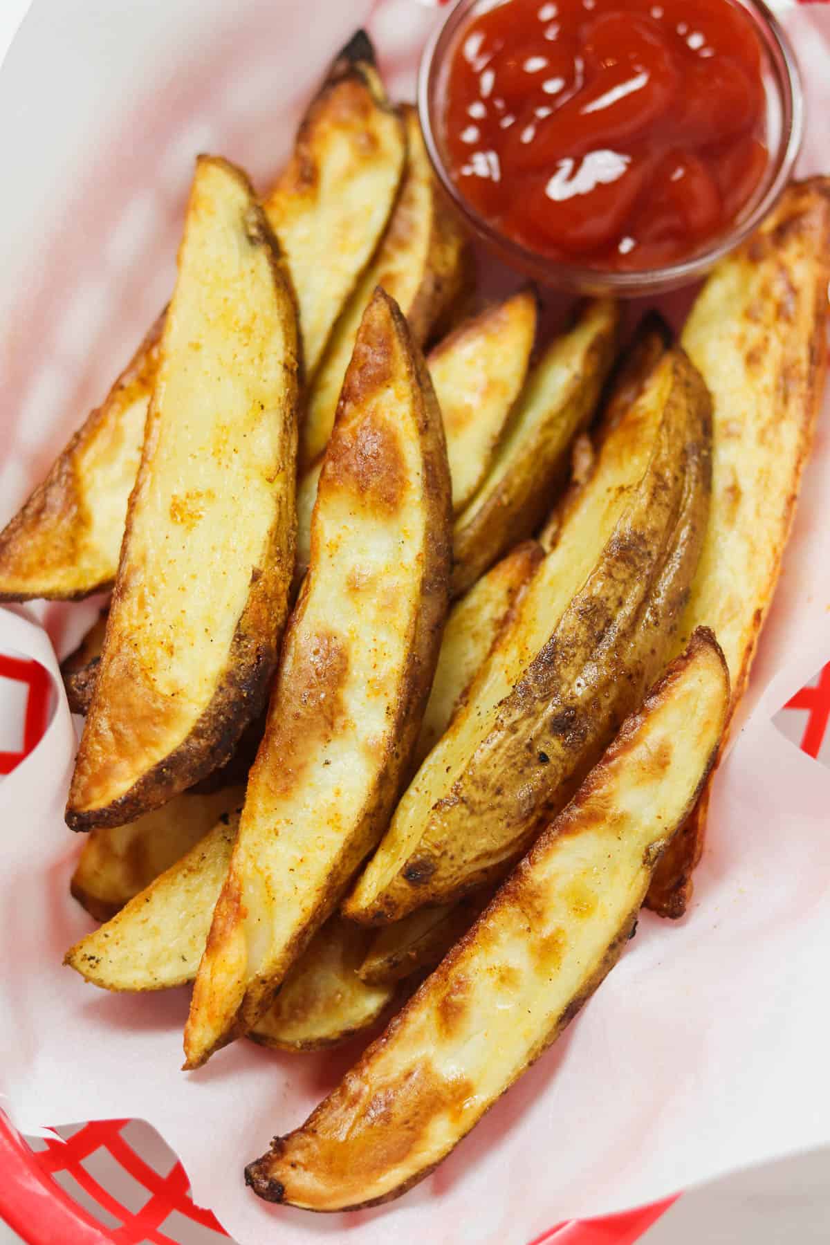 air fryer potato wedges in basket with ketchup