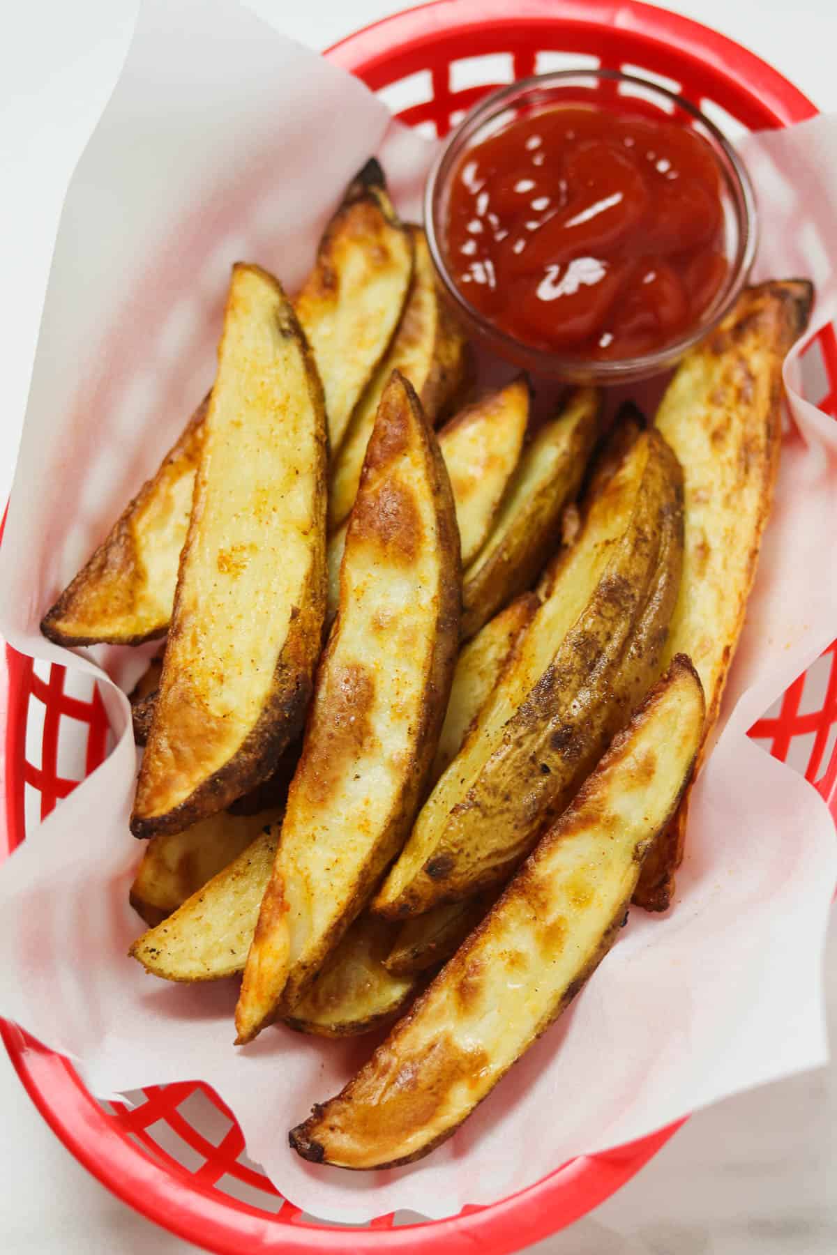 air fryer potato wedges in basket with ketchup