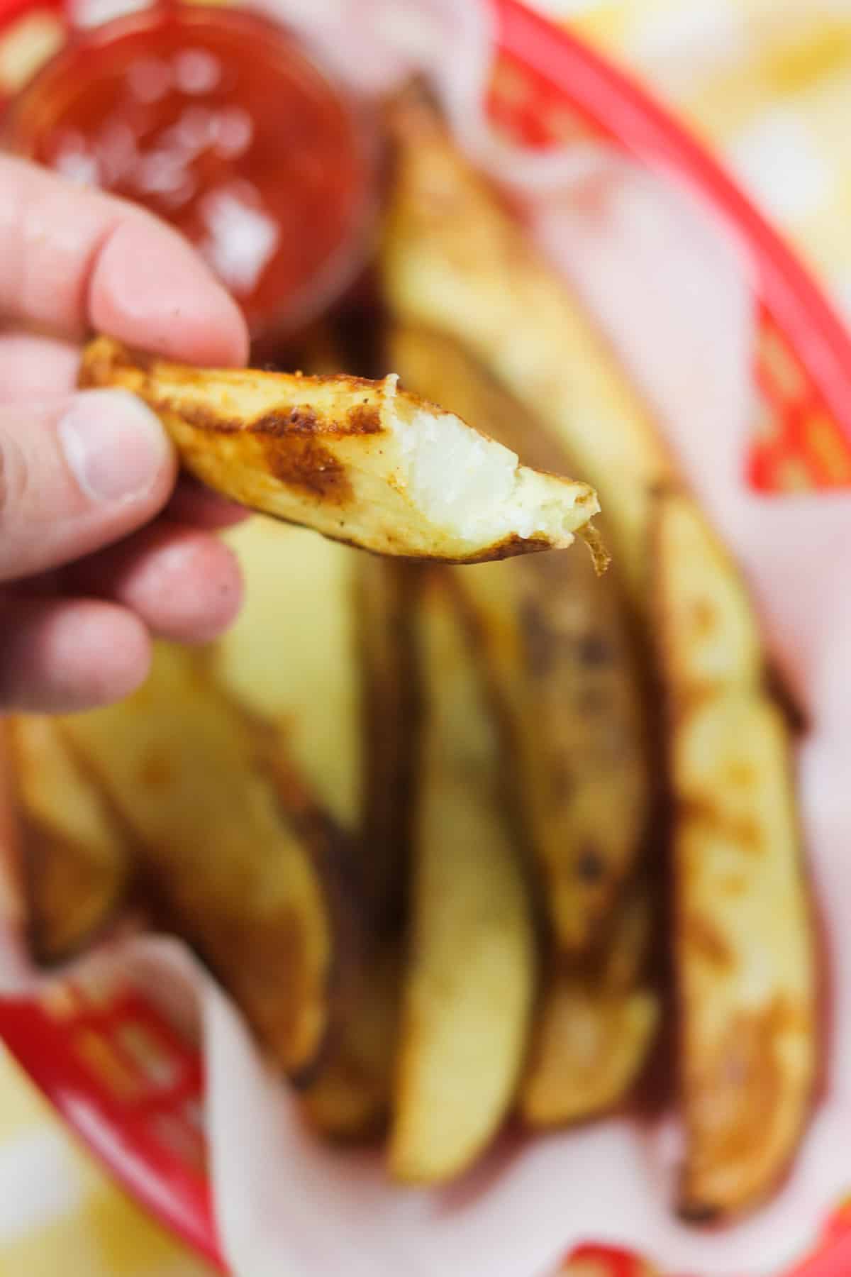 taking a bite of a potato wedge