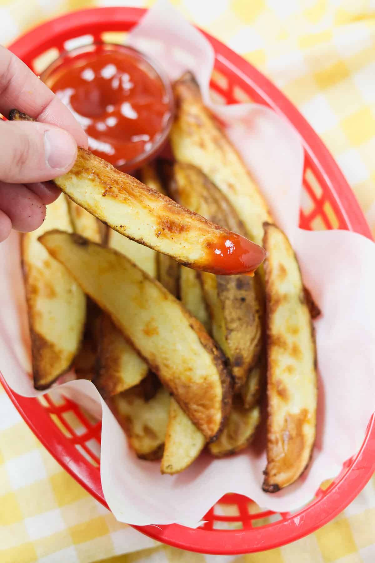 grabbing a potato wedge dipped in ketchup