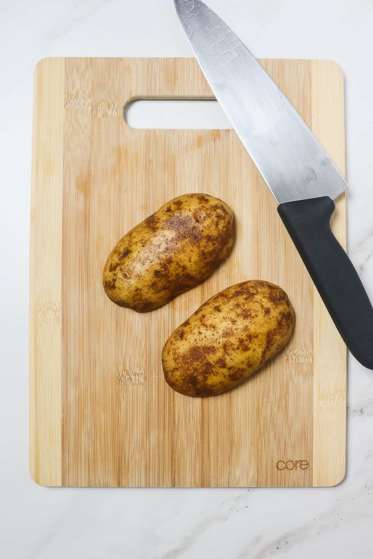 potato sliced in half on a wood cutting board