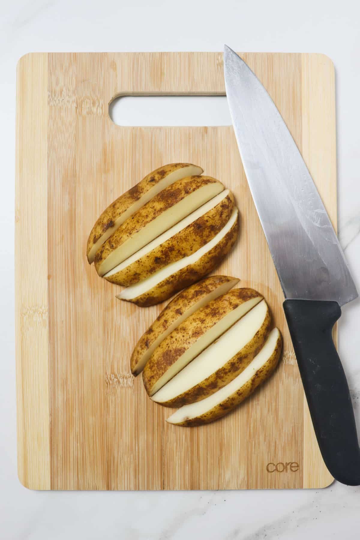 cutting potatoes into wedges on a wood cutting board