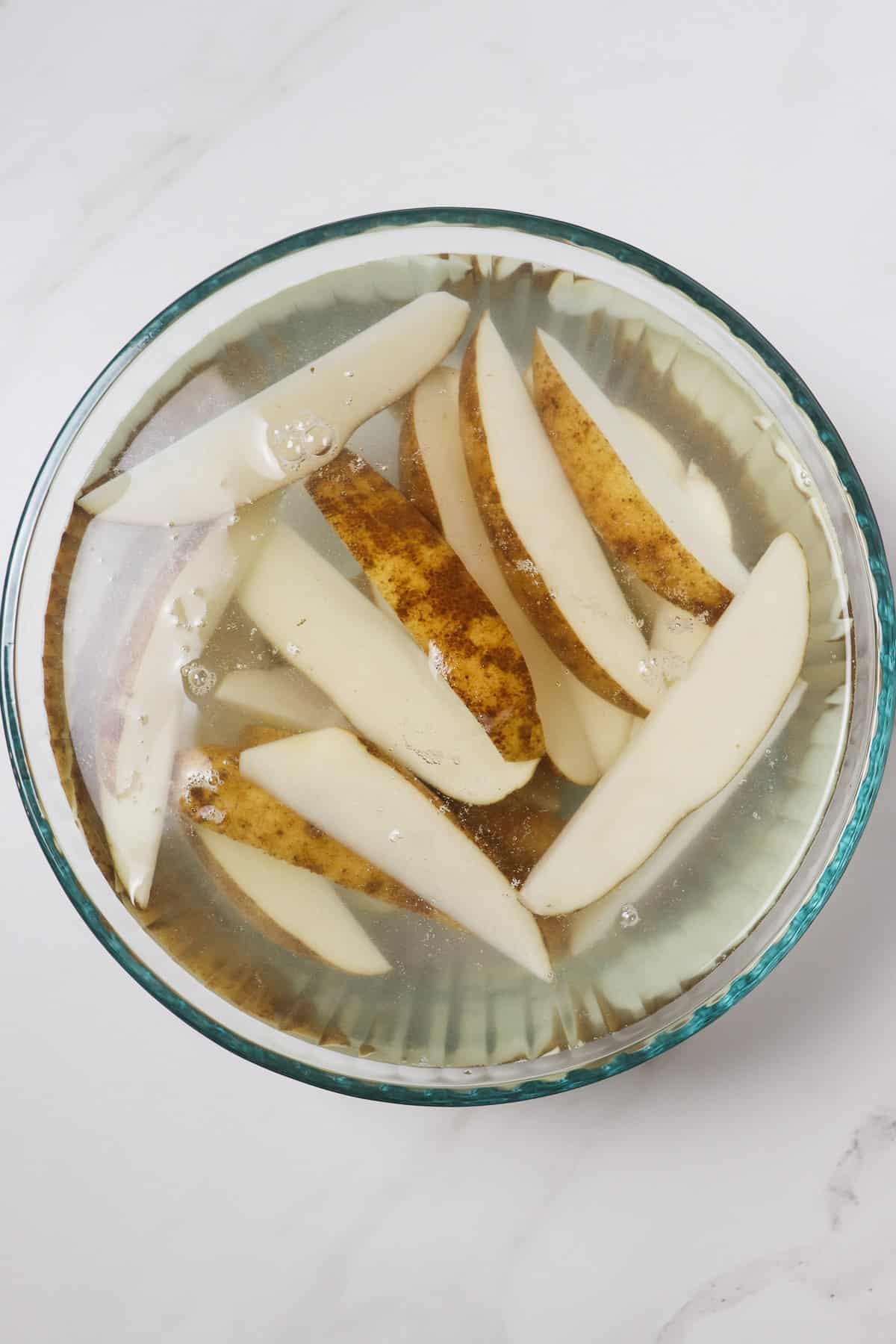 soaking potato wedges in a large glass bowl