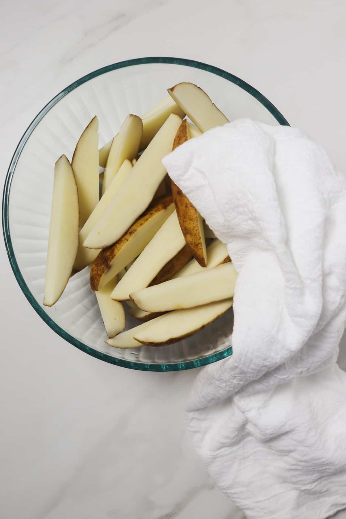 drying potato wedges in glass bowl with a white towel