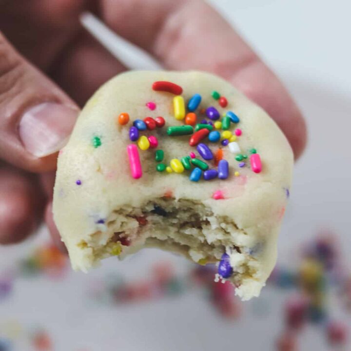 holding a piece of edible sugar cookie dough with a bite taken out