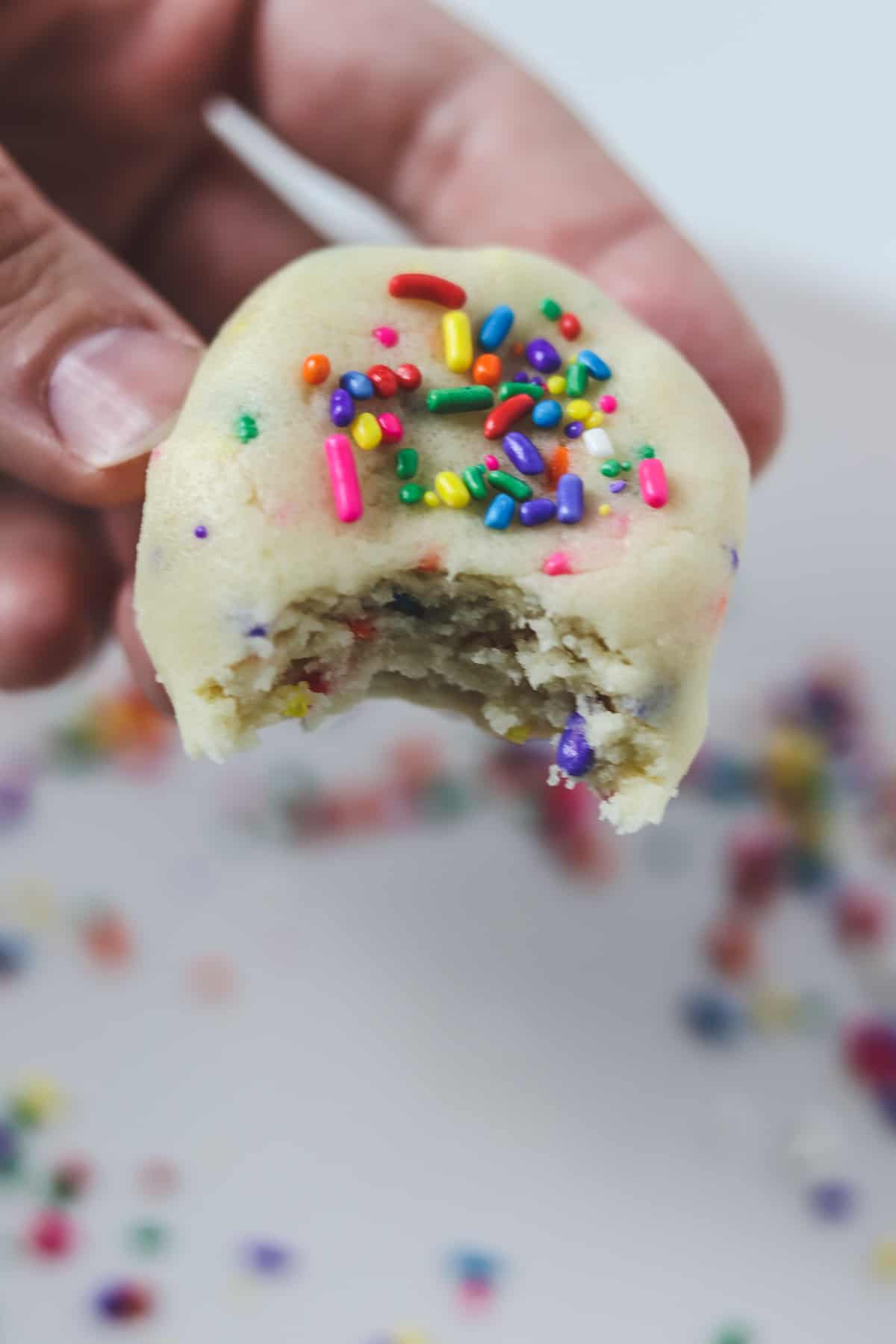 holding a piece of edible sugar cookie dough with a bite taken out