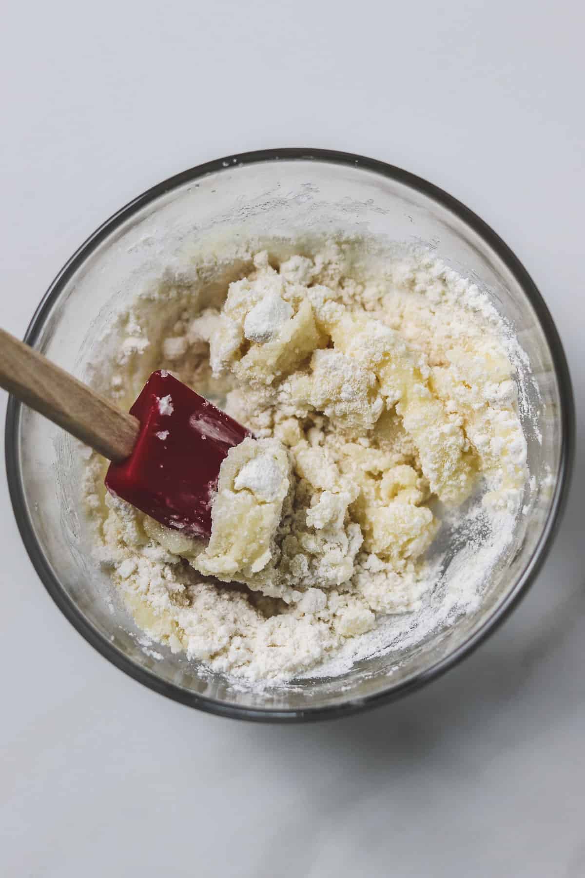 mixing flour with butter and sugar mixture in a small glass bowl