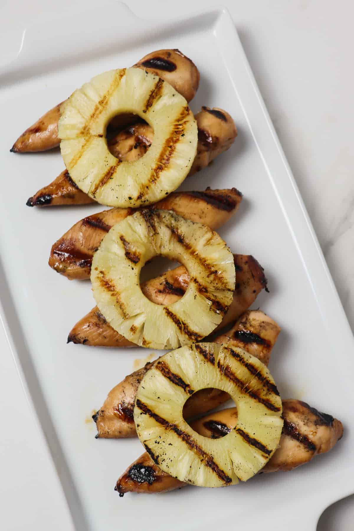 grilled pineapple chicken tenders on a white platter