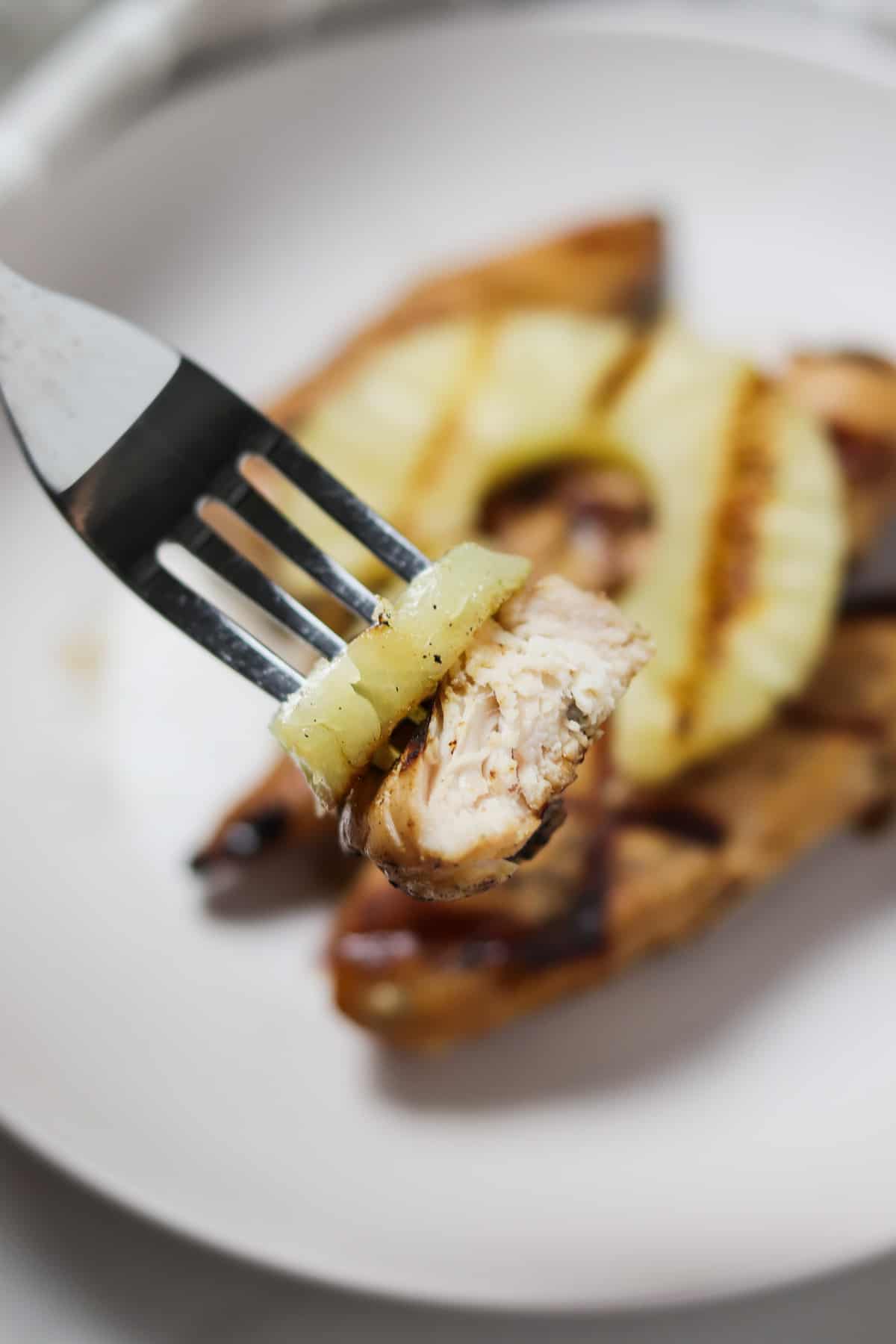 taking a bite of grilled pineapple chicken tenders with a fork