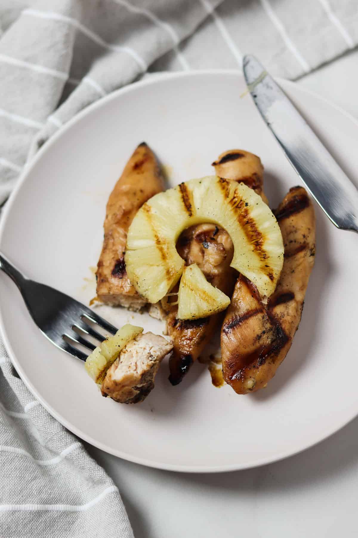 a plate of grilled pineapple chicken tenders with a bite loaded on a fork