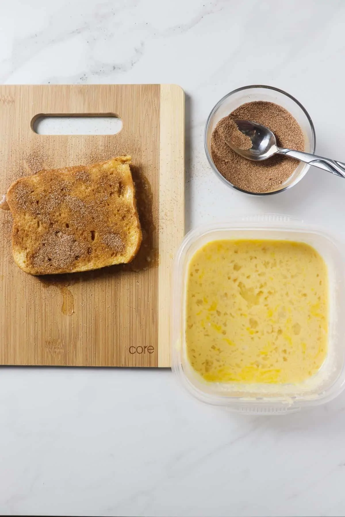 preparing french toast on a cutting board with an egg and milk mixture and cinnamon sugar mixture