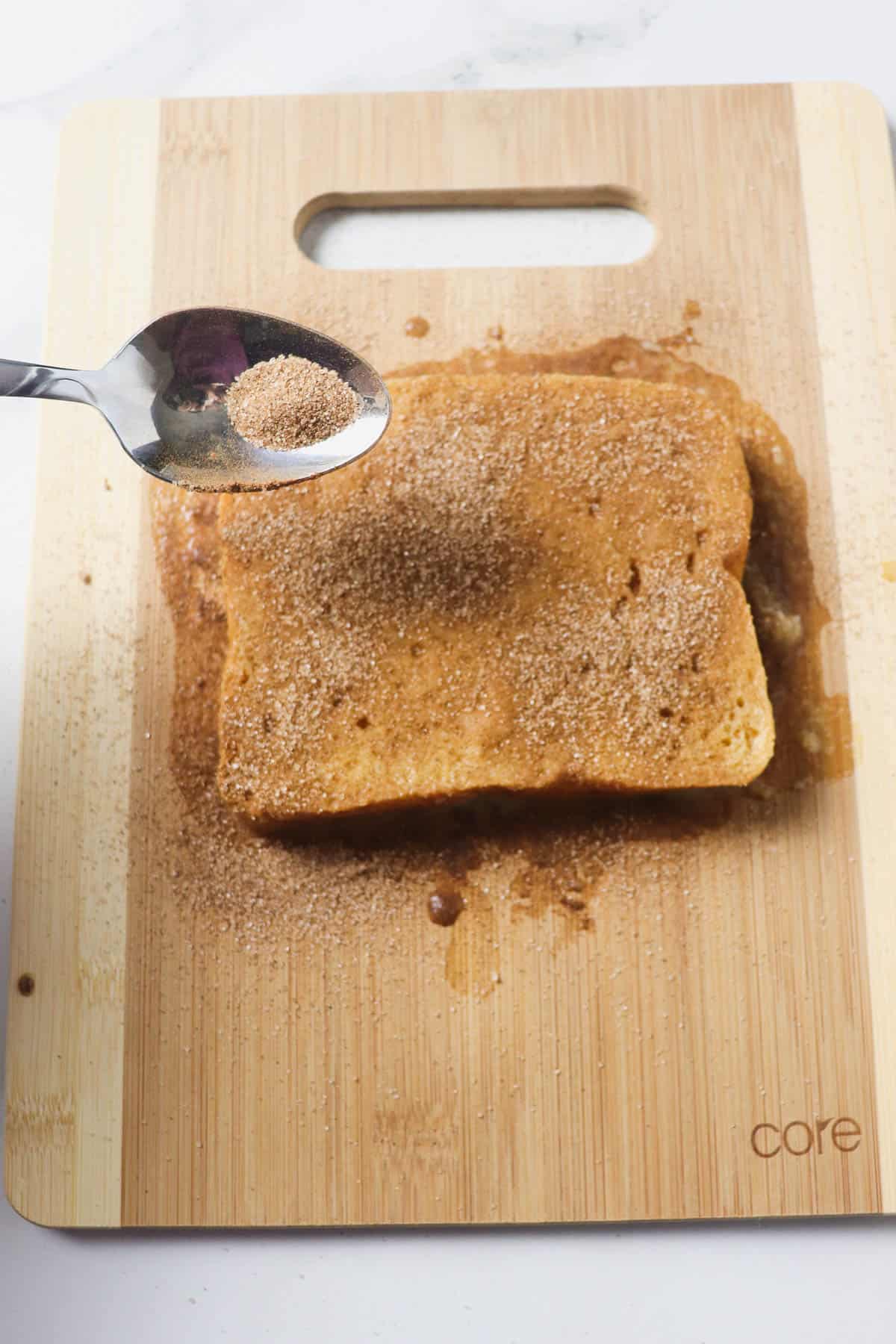 sprinkling cinnamon sugar mixture on french toast slices