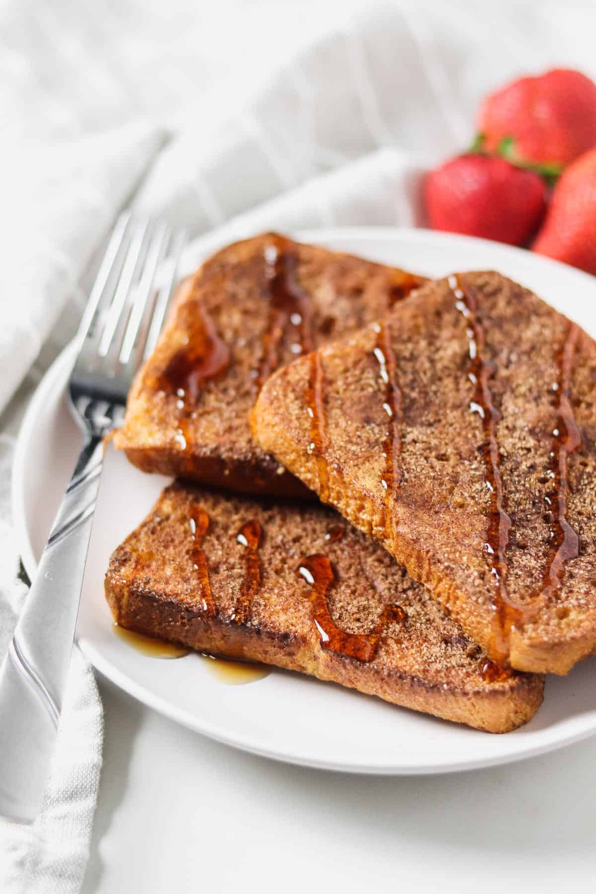 air fryer french toast on white plate with syrup drizzled on top