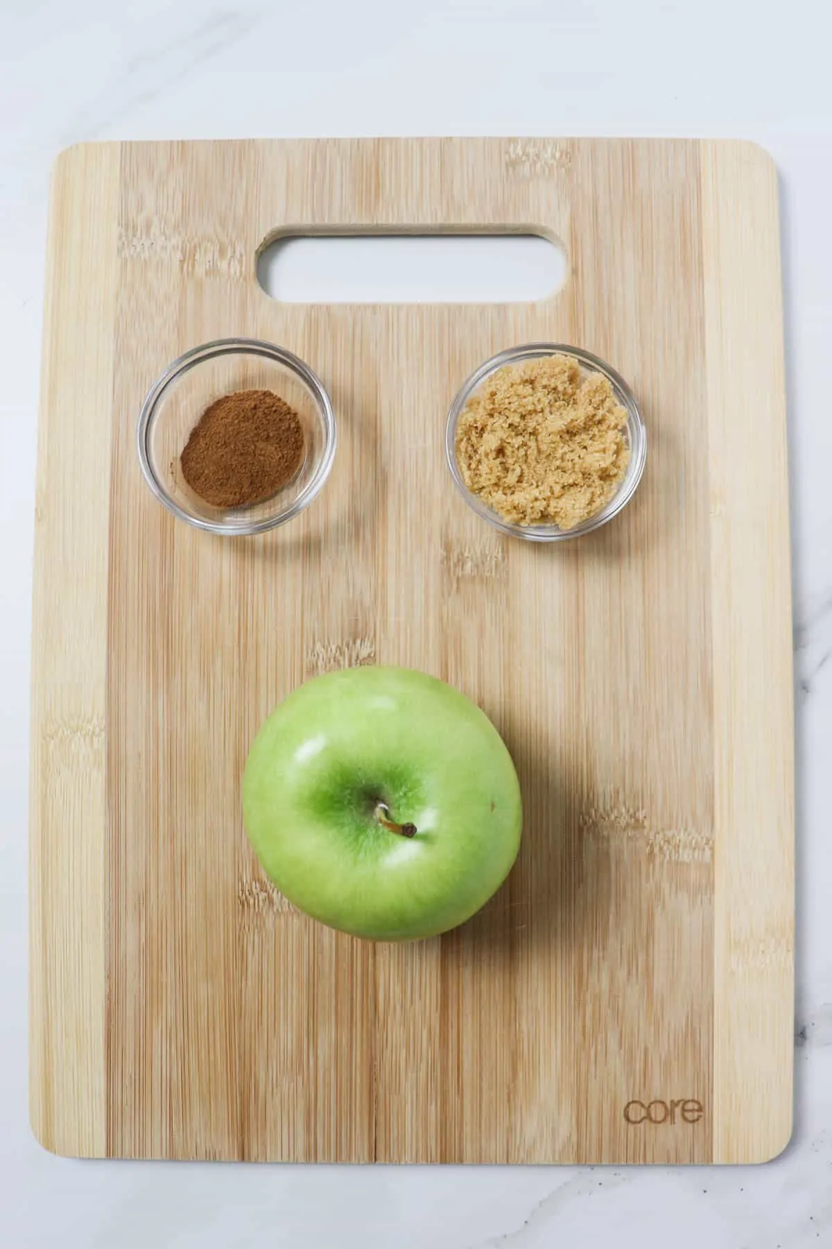 cinnamon, brown sugar, and granny smith apple on top of a wood cutting board