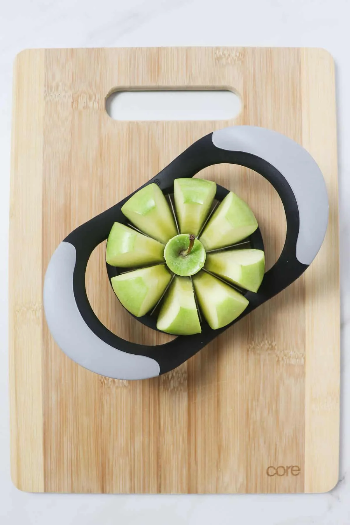 slicing an apple into wedges on top of a wood cutting board