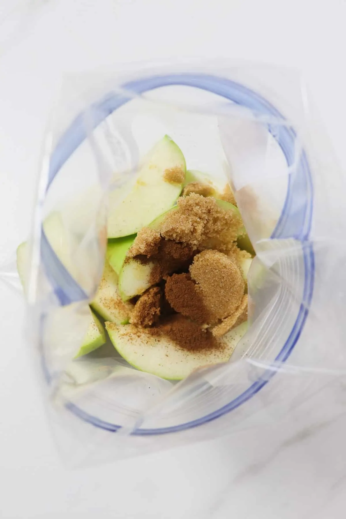 adding apple slices, cinnamon, and brown sugar to a plastic bag