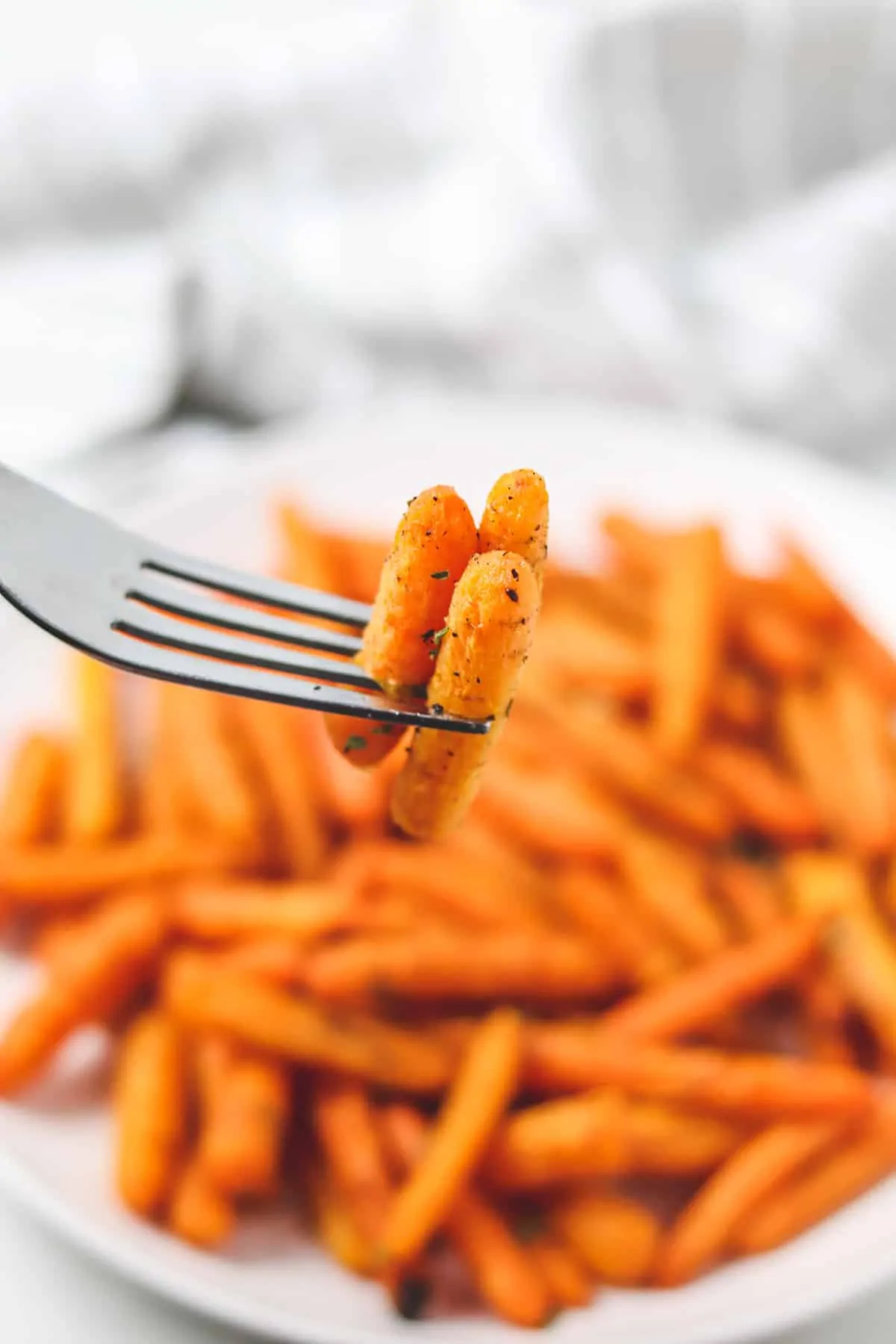 taking a bite of roasted carrots from a plate full of carrots