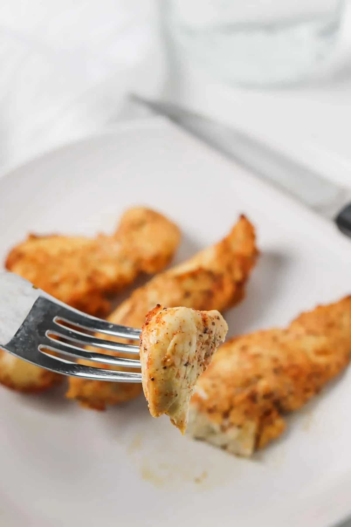 taking a bite of air fryer chicken tender with a fork