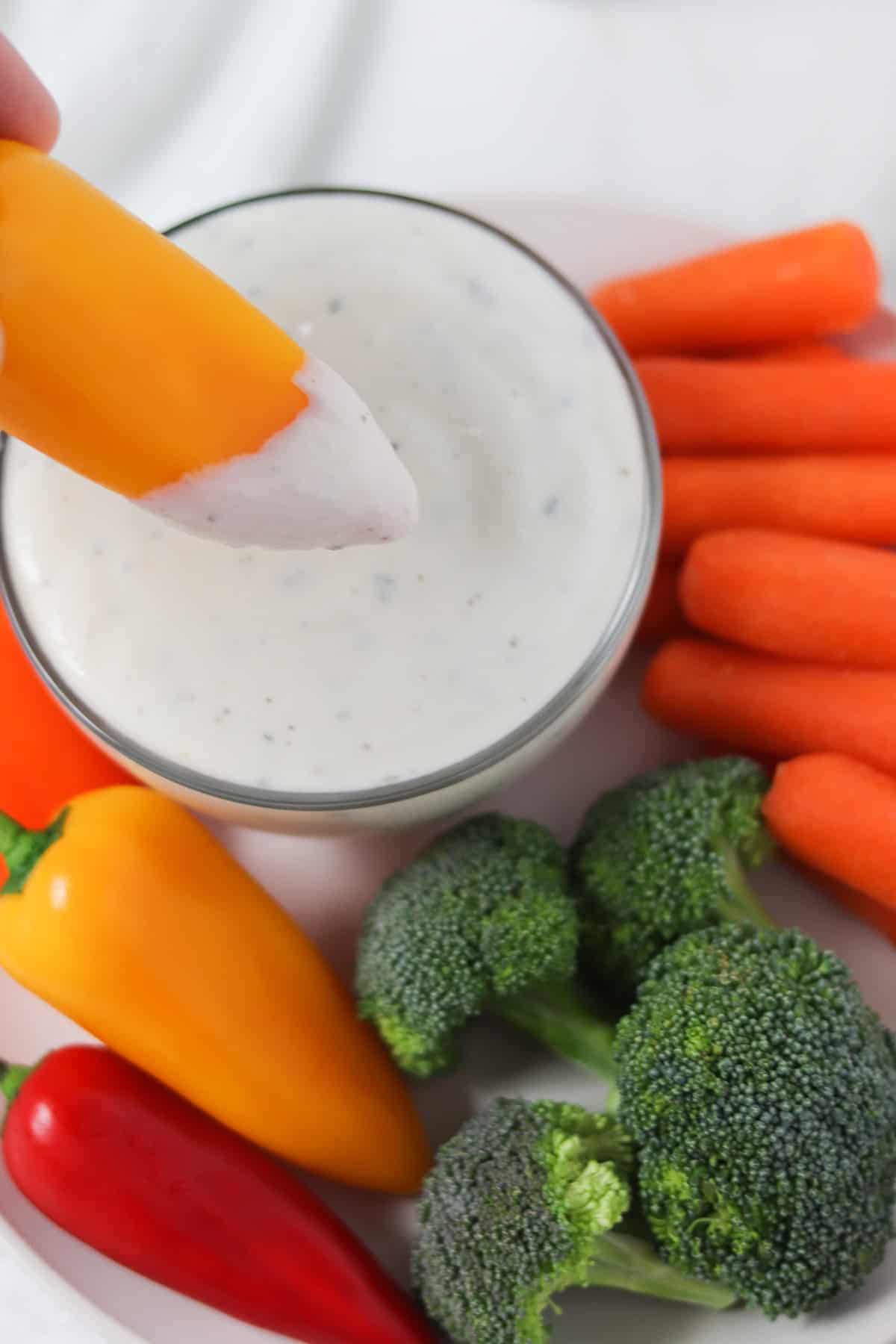 dipping a yellow mini pepper in ranch dip