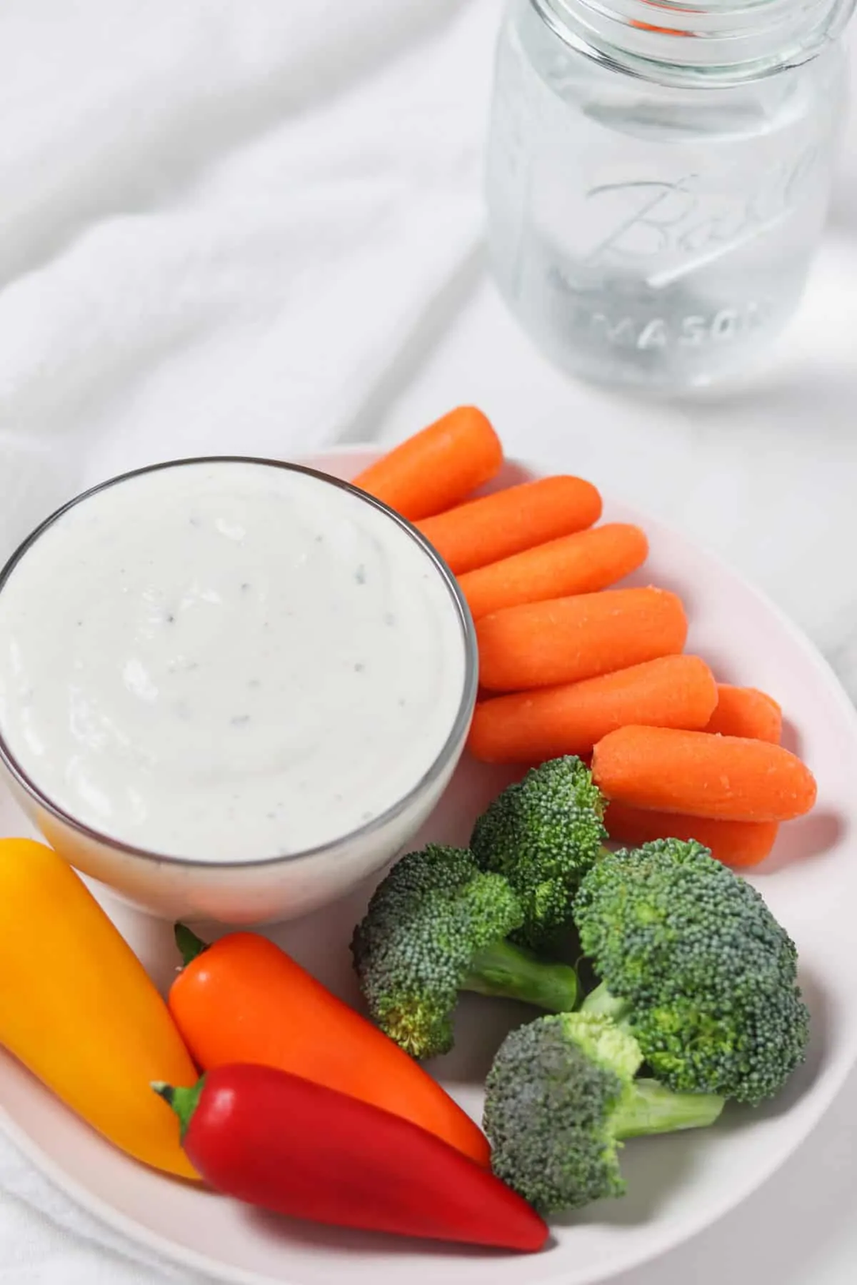 low calorie buttermilk ranch dip with a plate of vegetables and a glass of water